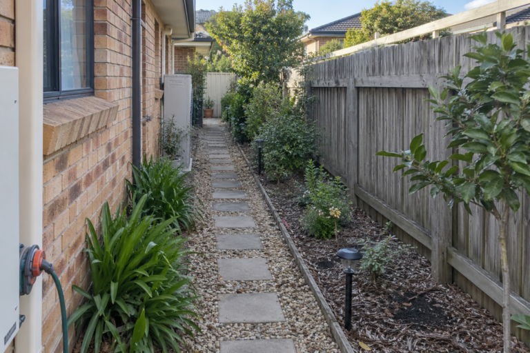Long side garden with path lights beside a timber fence